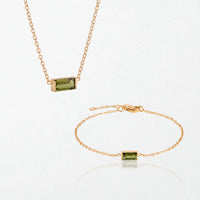 The Juno birthstone set for August: matching necklace and bracelet with peridot green baguette stones, in 14K gold-plated waterproof stainless steel