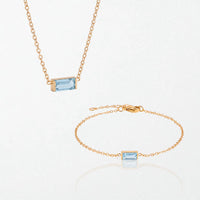 The Juno birthstone set for March: matching necklace and bracelet with aquamarine blue baguette stones, in 14K gold-plated waterproof stainless steel