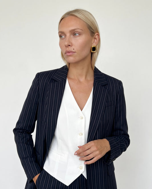 Woman in a navy pinstripe blazer and white vest wearing Sabine black and gold square statement stud earrings