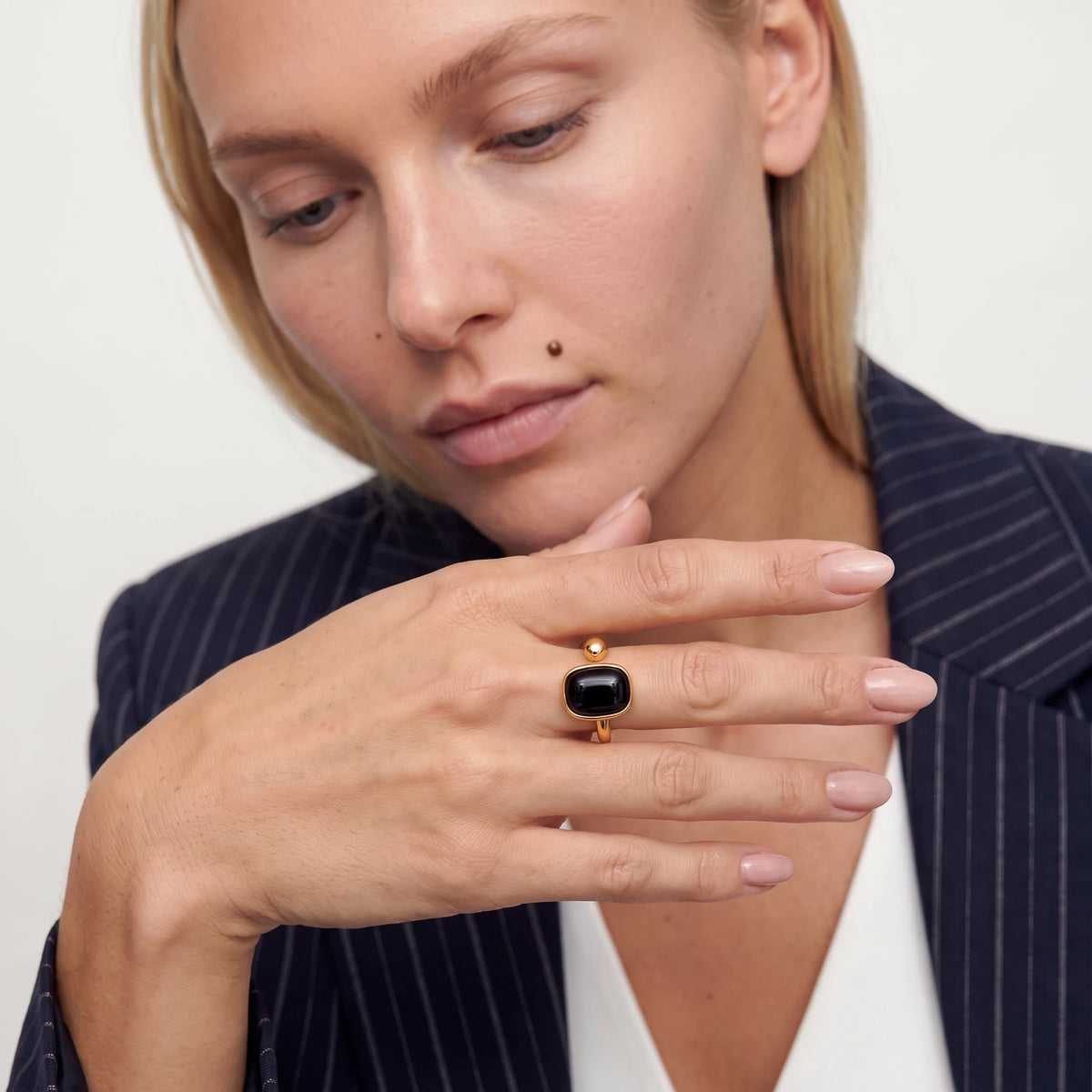 Woman looking down at the gold Odile black obsidian ring on her finger