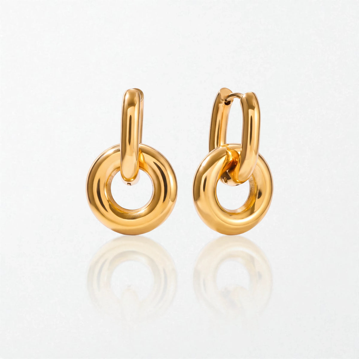 Pair of Alma drop hoops in 18K gold-plated waterproof stainless steel: a slim oval hinged hoop holding a chunky round donut ring