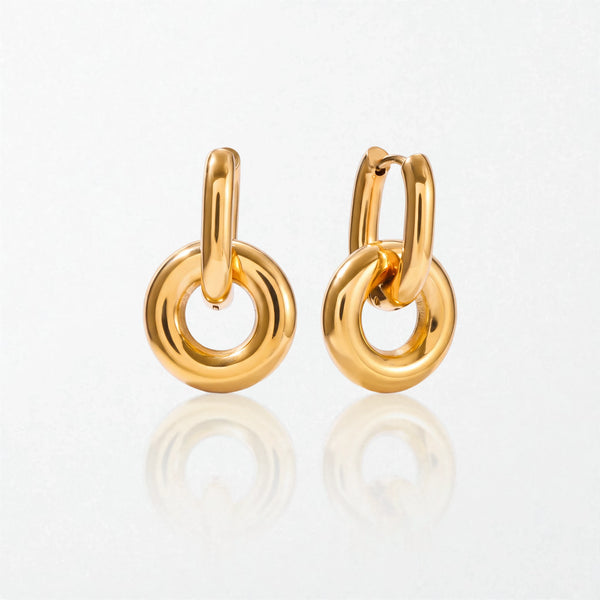 Pair of Alma drop hoops in 18K gold-plated waterproof stainless steel: a slim oval hinged hoop holding a chunky round donut ring