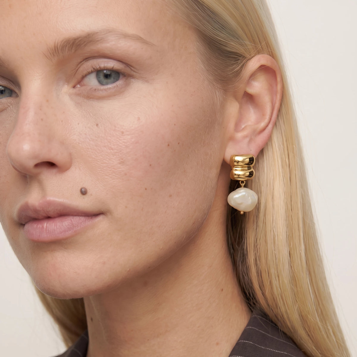 Close-up of a woman with a beauty mark wearing a Bianca earring, an ivory resin drop under a stacked gold stud