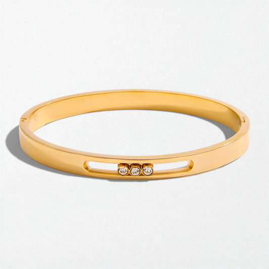 Gold sliding crystal bangle positioned to show the channel depth and polished finish