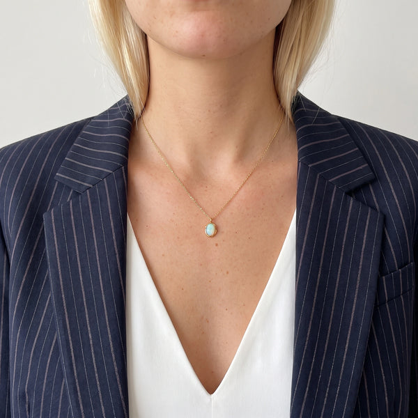 Ivy molten opal pendant necklace in 18K gold-plated waterproof stainless steel, worn with a navy pinstripe blazer and white top