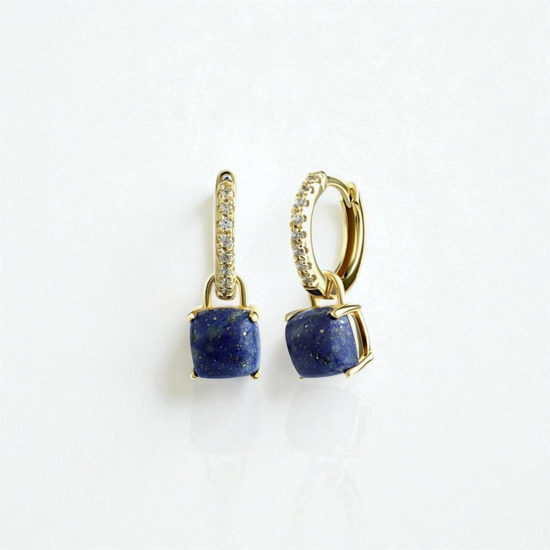 Gold earrings with a blue lapis lazuli gemstone on a white background