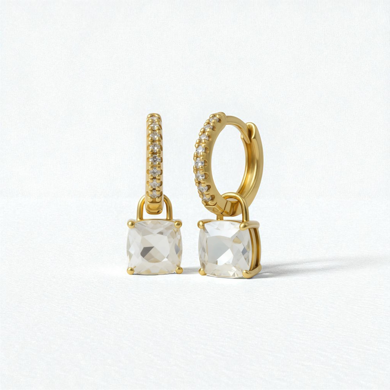 Gold hoop earrings with clear gemstones on a light gray background