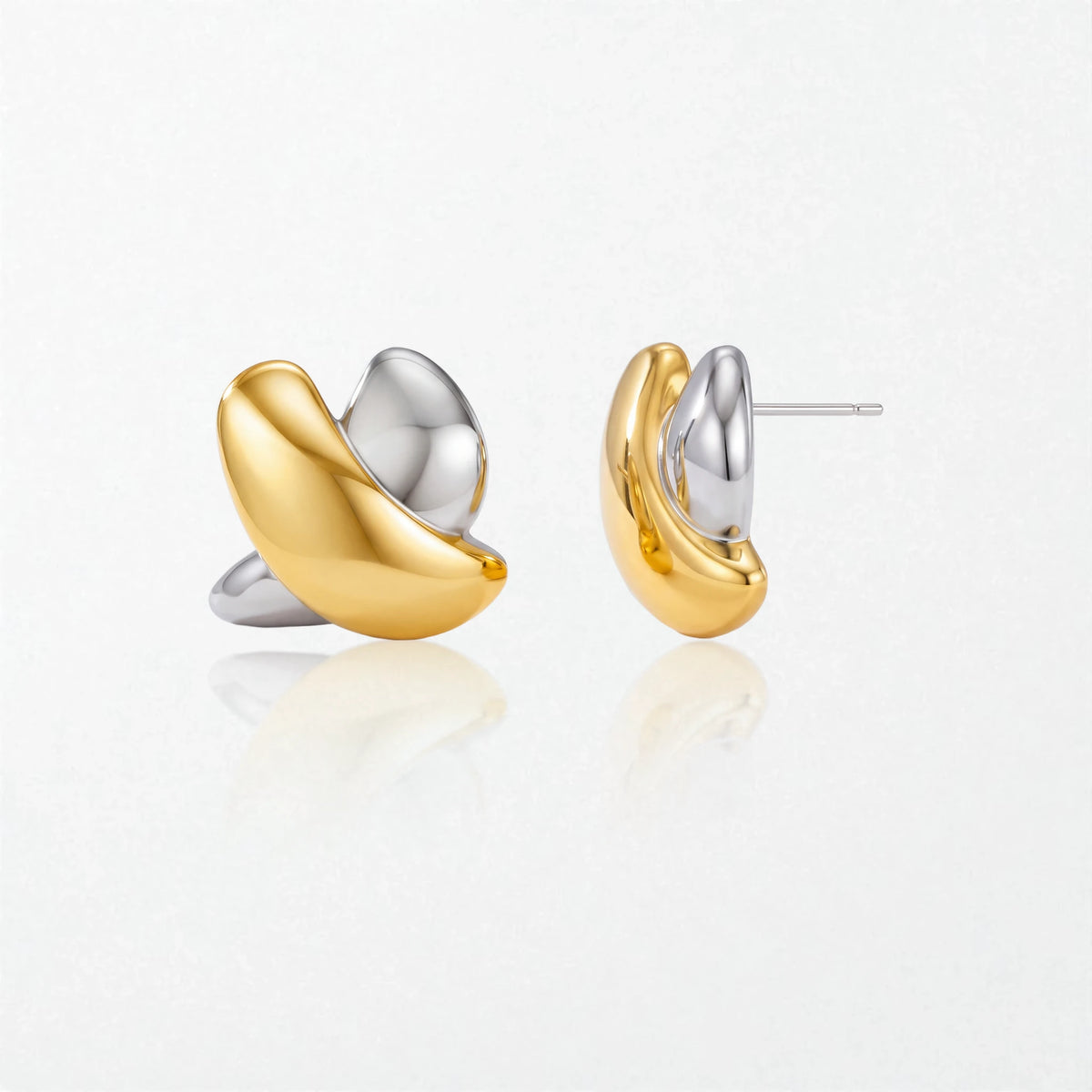 Pair of Esme sculptural crossed stud earrings in duo tone: a glossy gold loop crossing a polished silver loop