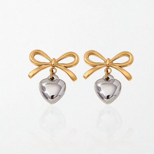 Pair of Eloise bow and heart drop earrings in duo tone: gold bows with polished silver puffed hearts